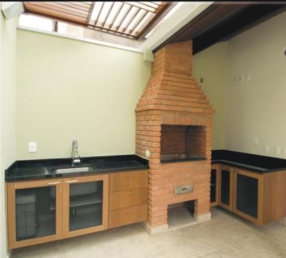 Área gourmet planejada com bancada e armários ao lado da churrasqueira
