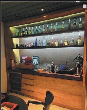Bar planejado com prateleiras iluminadas e bancada de madeira